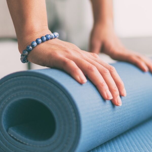 Yoga at home active lifestyle woman rolling exercise mat in living room for morning meditation yoga banner background.